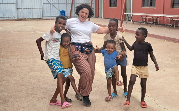 Grupa dzieci bawiących się z dorosłą osobą na podwórku.