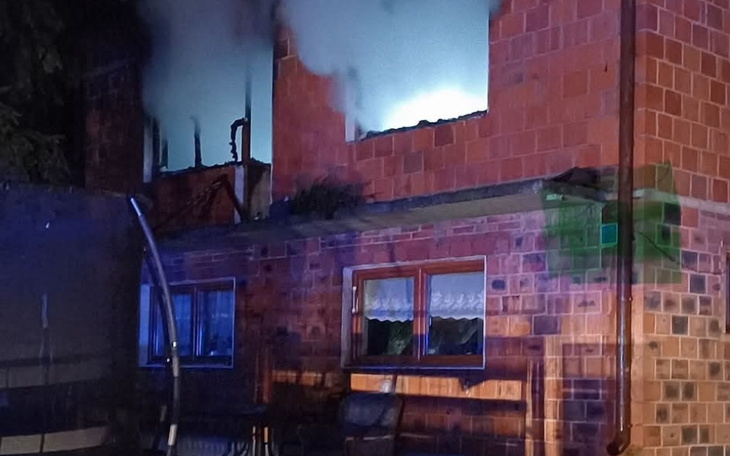 Dom w płomieniach, z dymem wydobywającym się z okien.