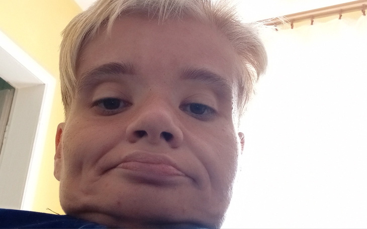 Portret osoby z krótkimi włosami, patrzącej w stronę kamery.