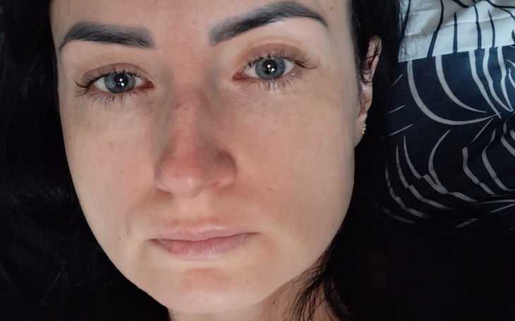 Zbliżenie na twarz kobiety leżącej na łóżku.