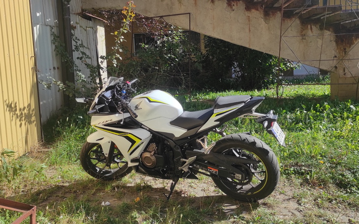 Biały motocykl zaparkowany w trawie.