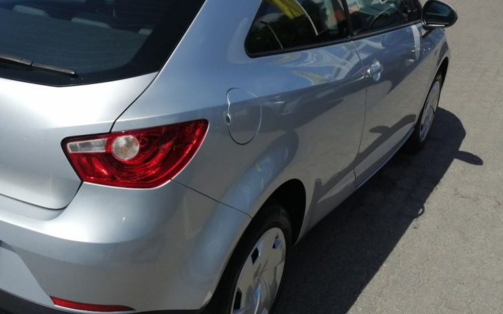 Tył srebrnego samochodu, widoczna lampa i koło.