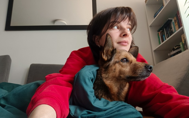 Kobieta leżąca na kanapie z psem, oboje wpatrzeni w dal.