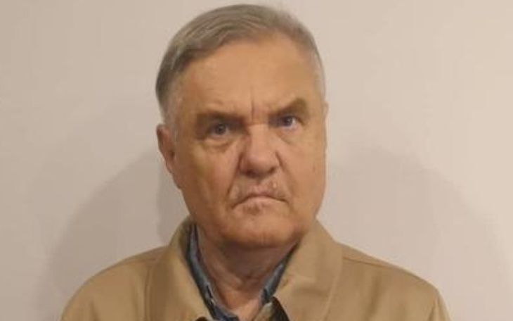 Starszy mężczyzna z poważnym wyrazem twarzy na jasnym tle.