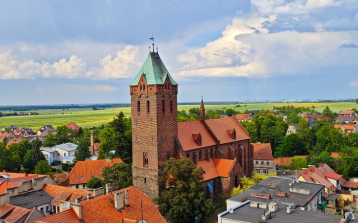 Widok na średniowieczny kościół z zielonym dachem w otoczeniu domów.