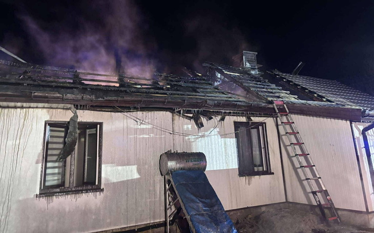 Zniszczony dach domu po pożarze, z widoczną drabiną.