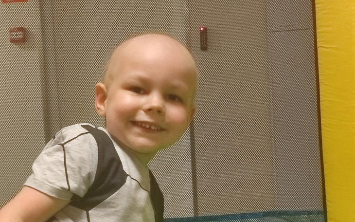 Uśmiechnięty chłopiec z łysą głową w parku zabaw.