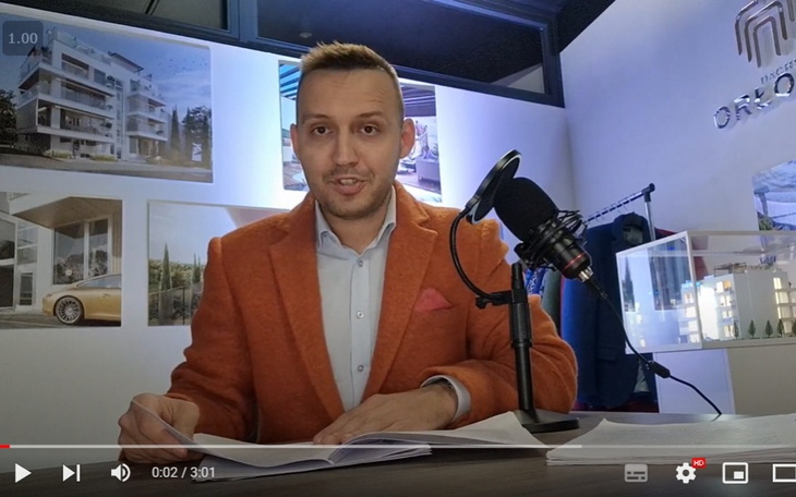 Mężczyzna w pomarańczowym garniturze, prowadzący prezentację.