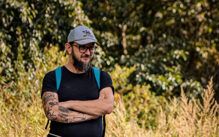 Mężczyzna z tatuażami w otoczeniu zieleni.