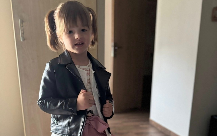 Mała dziewczynka w skórzanej kurtce, pozująca do zdjęcia.