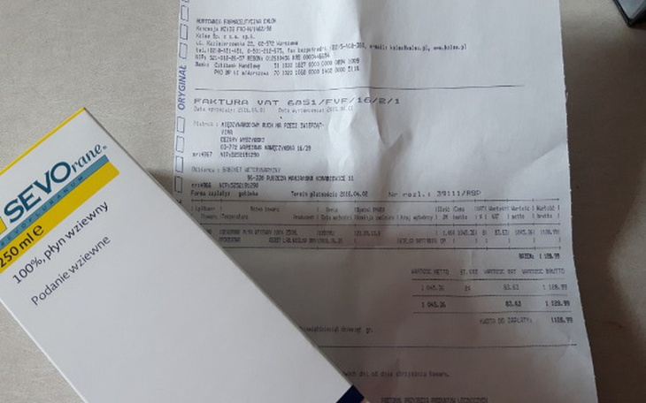 Opakowanie leku i faktura na stole, w tle dokumenty.