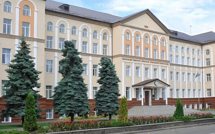 Budynek uczelni wyższej z zielonymi drzewami w otoczeniu.