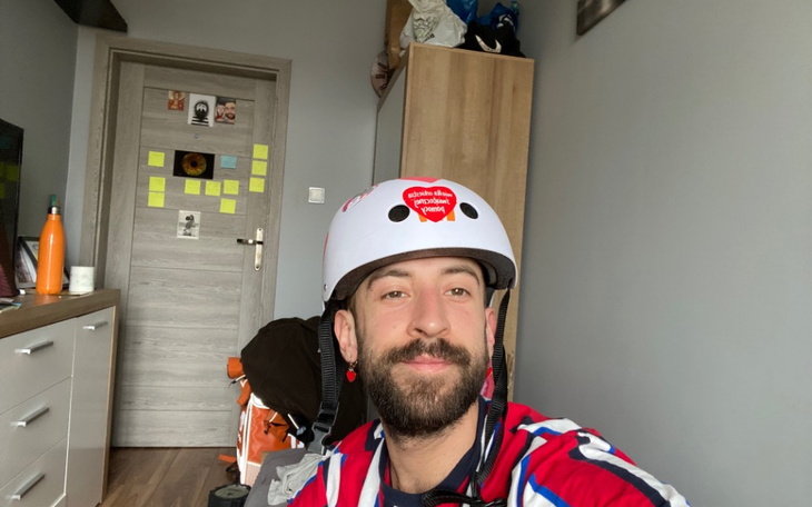 Mężczyzna w kasku, uśmiechający się w swoim pokoju.