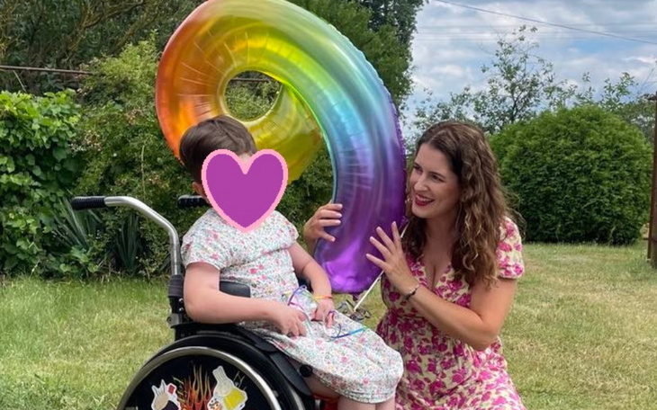 Dziecko w wózku inwalidzkim z kolorowym balonem.