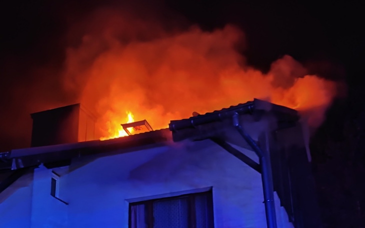 Płonący budynek w nocy, z dymem i ogniem.