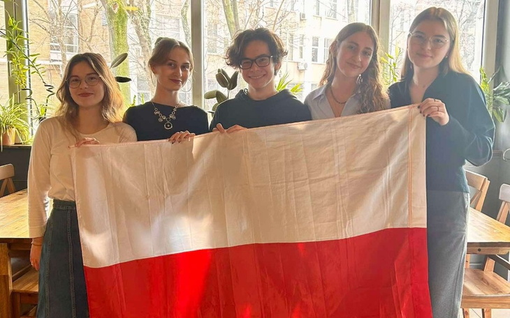 Grupa kobiet trzymająca flagę Polski w kawiarni.