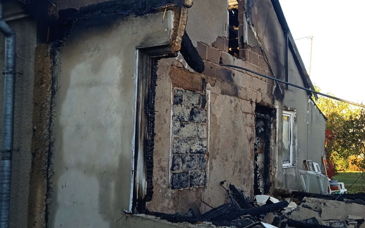 Zniszczony budynek po pożarze, z widocznymi uszkodzeniami.