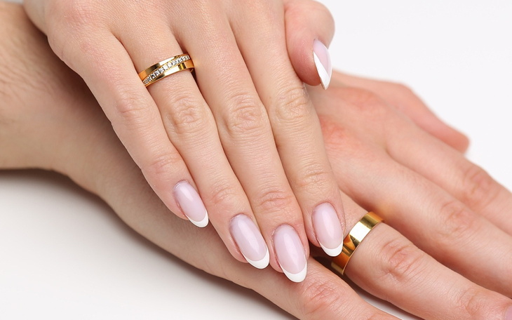 Dłonie z manicurem, na palcach złote pierścionki.