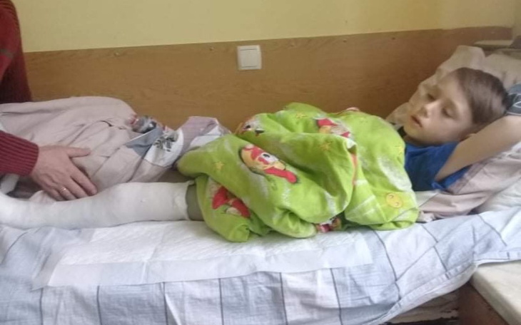 Chłopiec leżący w łóżku, przykryty kolorową kołdrą.