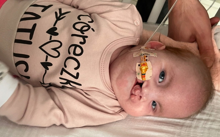 Mała dziewczynka z uśmiechem, leżąca w łóżku.