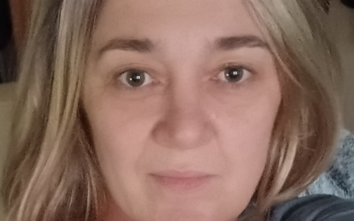 Portret kobiety z długimi włosami, uśmiechającej się do kamery.