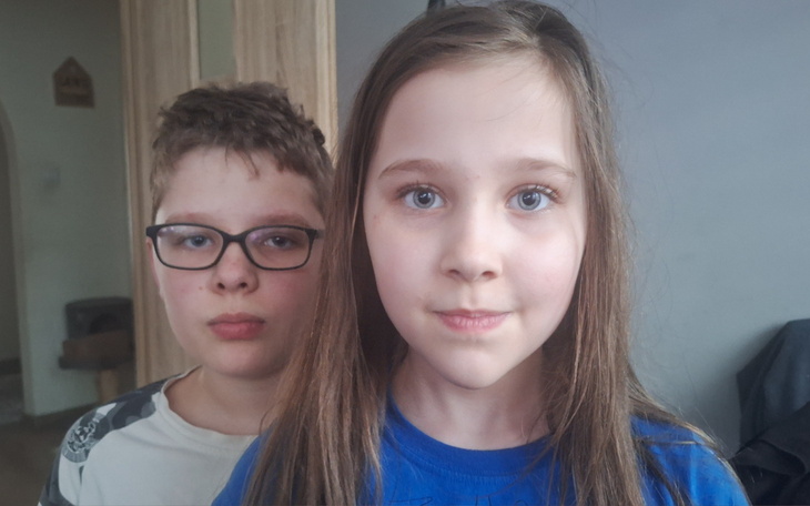 Dwoje dzieci stojących blisko siebie, patrzących w obiektyw.