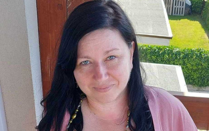 Portret kobiety z uśmiechem, w naturalnym otoczeniu.