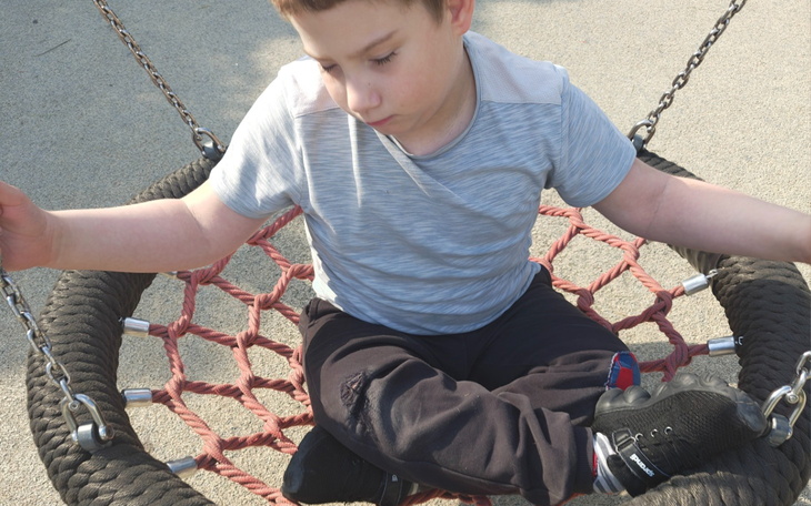 Chłopiec bawiący się na huśtawce w parku.