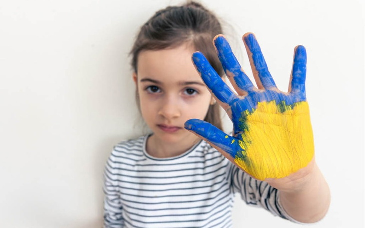 Dziewczynka z malowaną dłonią w kolorach ukraińskiej flagi.