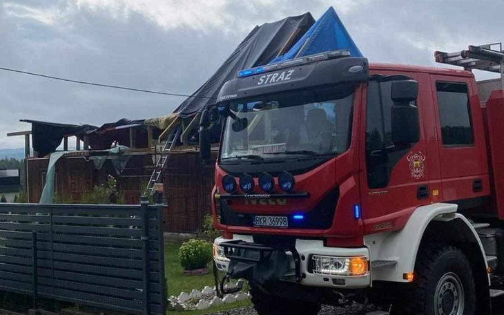 Wóz strażacki przed domem z uszkodzonym dachem.