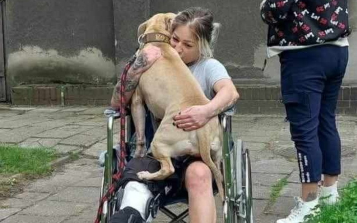 Kobieta w wózku inwalidzkim przytula psa.