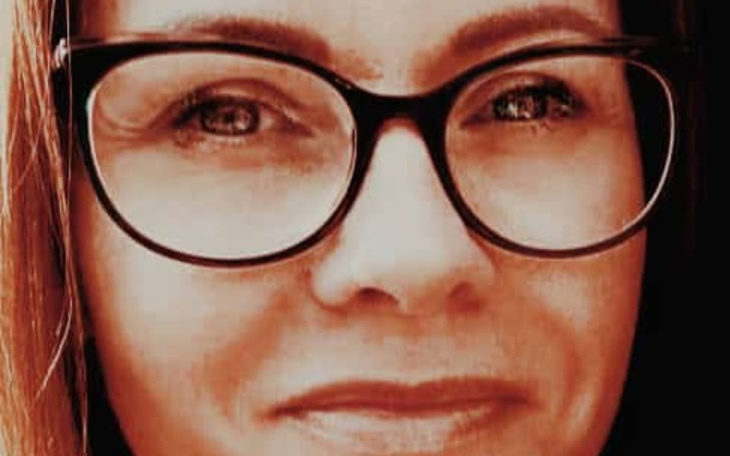 Close-up of a woman wearing glasses, smiling softly.