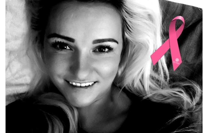 Kobieta z uśmiechem, z różową wstążką symbolizującą walkę z rakiem.