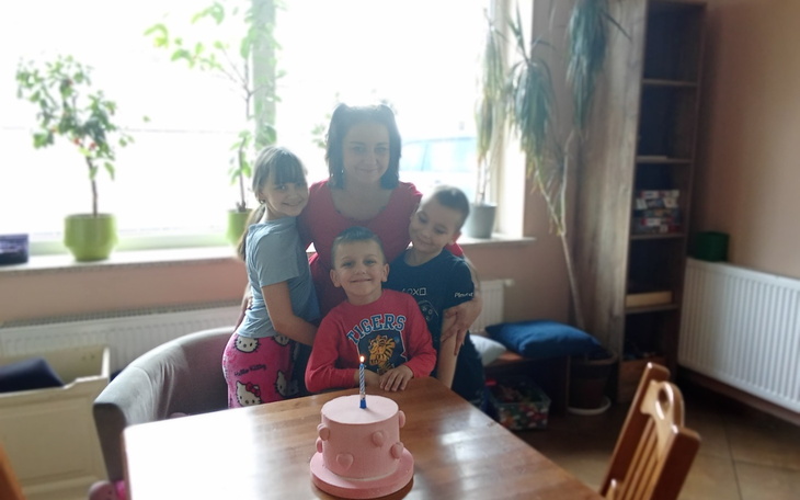 Rodzina świętująca urodziny przy stole z tortem.
