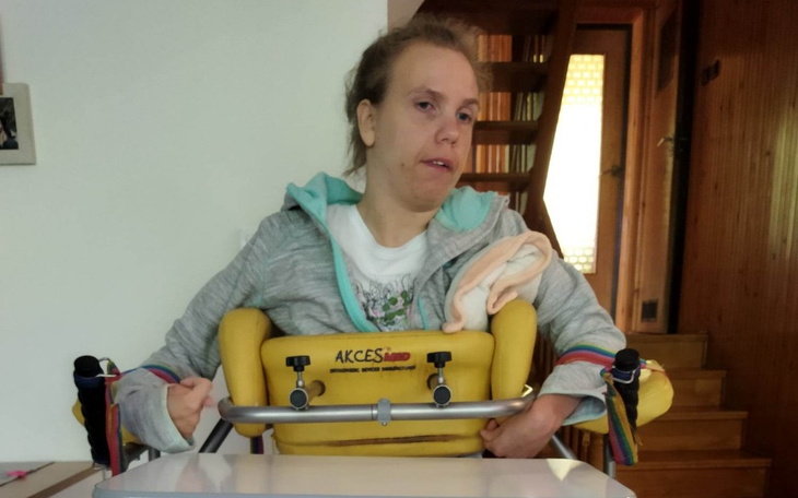 Kobieta w wózku, uśmiechająca się do kamery.