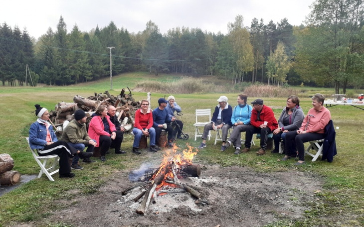 Grupa ludzi przy ognisku w plenerze.