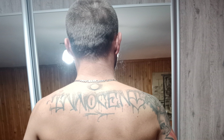 Mężczyzna z tatuażem na plecach, patrzący w lustro.