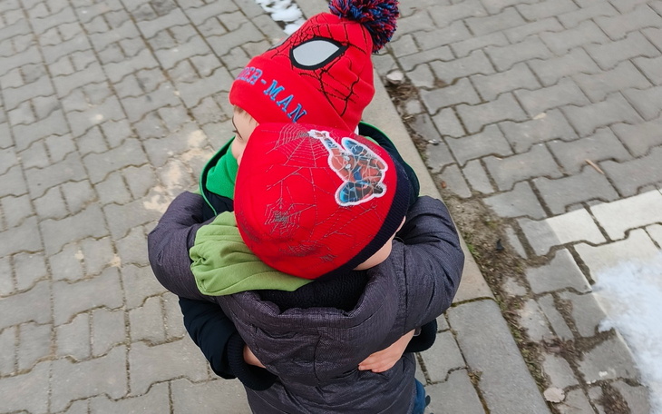 Dzieci przytulające się w czapkach z postacią Spider-Mana.