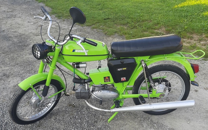 Zielony motocykl ROMET na tle trawnika.