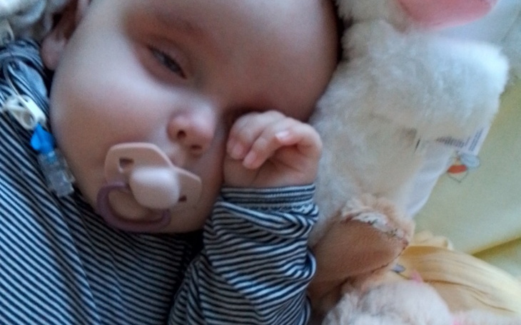 Małe dziecko śpiące z smoczkiem, przytulone do pluszaka.