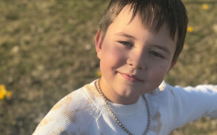 Chłopiec uśmiechający się na tle zielonej trawy.