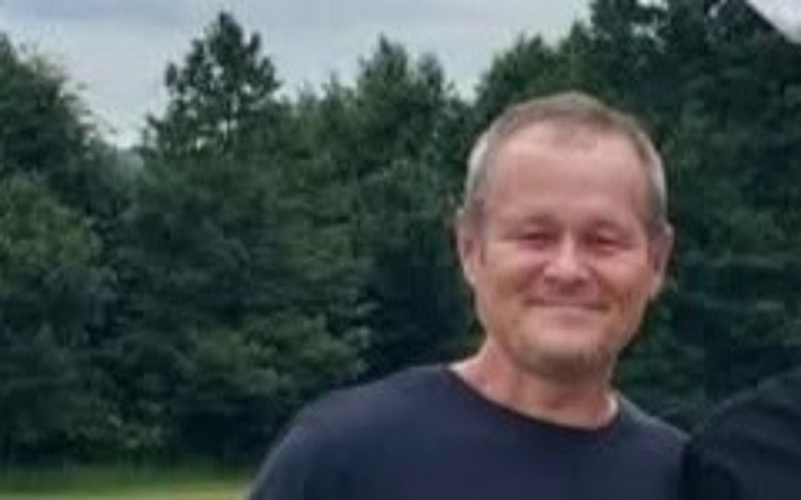 Uśmiechnięty mężczyzna na tle zieleni.