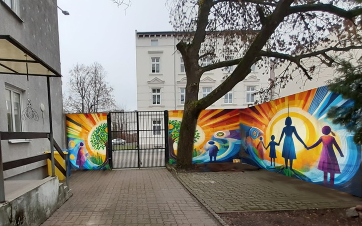 Mur z kolorowymi muralami przedstawiającymi postacie.