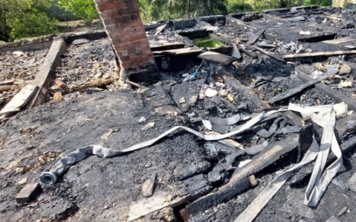 Zniszczony dach budynku po pożarze, z pozostałościami materiałów.