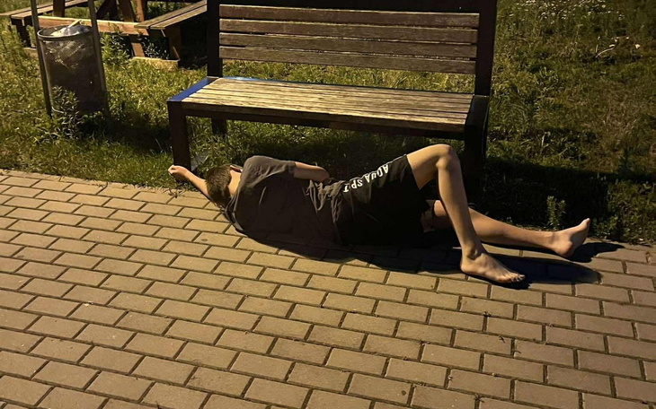 Osoba leżąca na chodniku, odpoczywająca w parku.