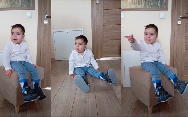 Mały chłopiec w białej koszuli, siedzący na kanapie.