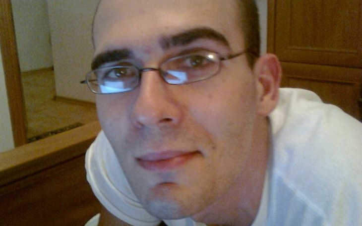 Mężczyzna w okularach, uśmiechający się do kamery.