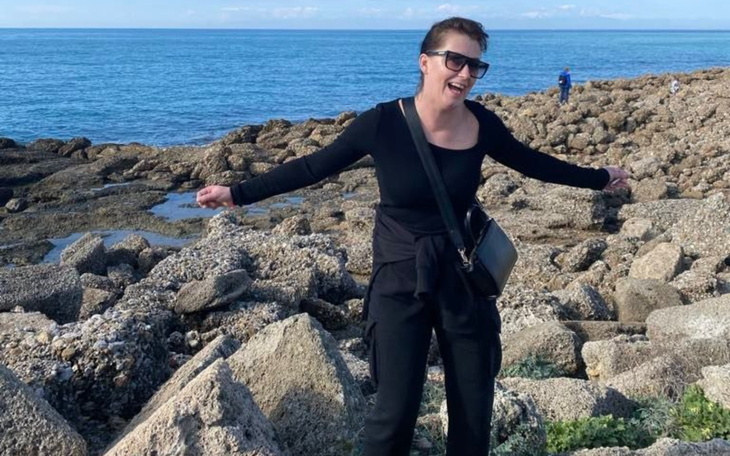 Kobieta na plaży, radosna i pełna energii, w otoczeniu skał.