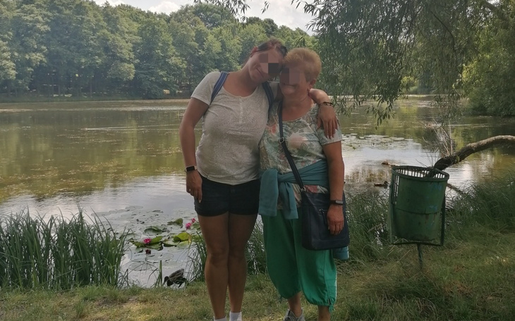 Dwie kobiety przy jeziorze, cieszące się wspólnym czasem na łonie natury.