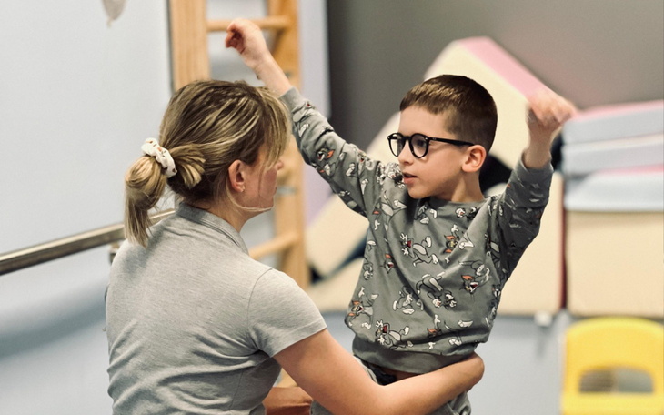 Dziecko w ramionach dorosłego, cieszy się z zabawy.